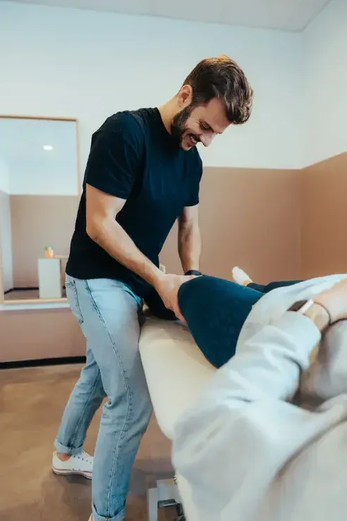 Kinésithérapeute mobilisant la jambe d’un patient sur la table de soins